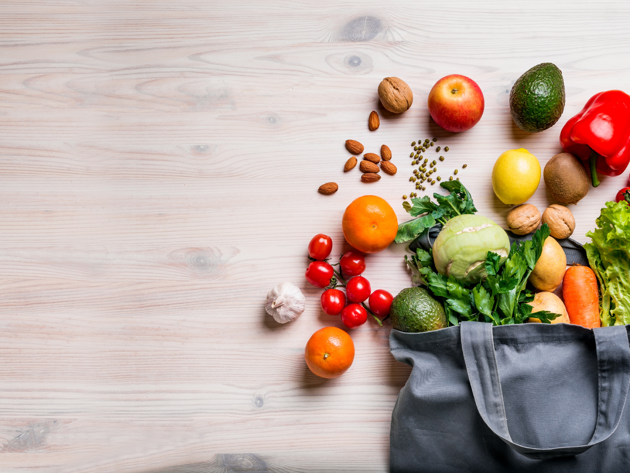 Shopping bag overflowing with fruits and vegetables and spread out on a counter