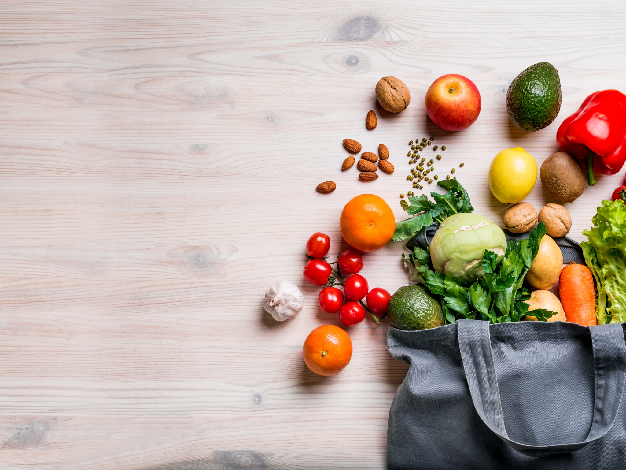 Shopping bag overflowing with fruits and vegetables and spread out on a counter 